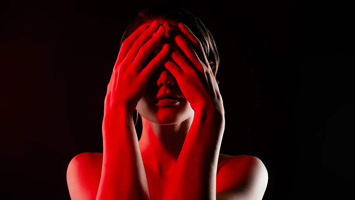 A woman covering eyes with her hands in fear that red led light could damage eyesight